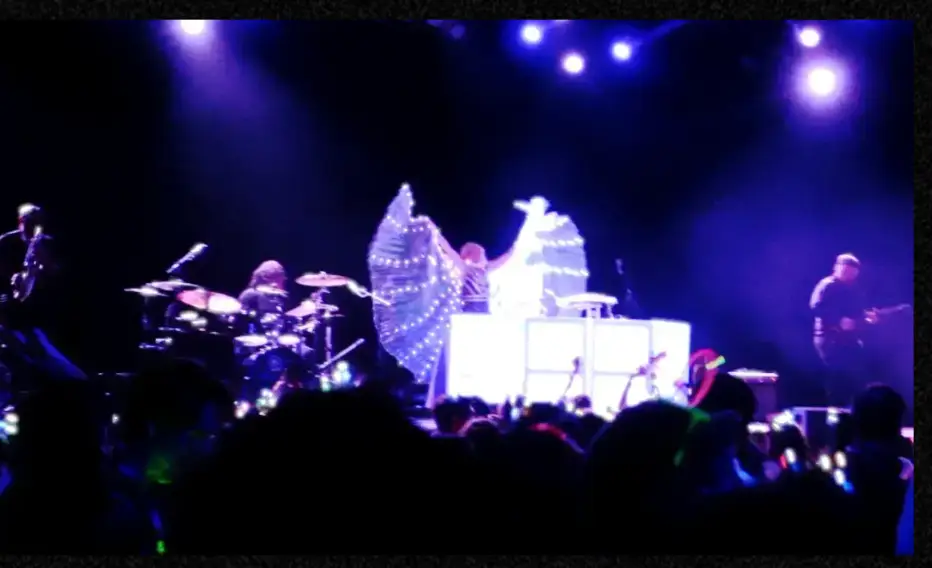 DeeJay Shelly performing with The ElectriX at The Fillmore Philadelphia, hand raised, with electric guitar, drummer, saxophone, and the crowd visible – female DJ and live band entertainment